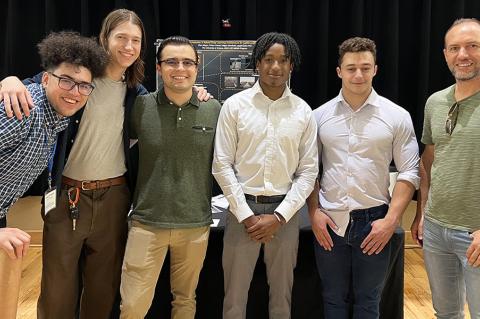 6 people stand in front of a research poster