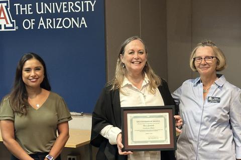 Three people pose with an award certificate