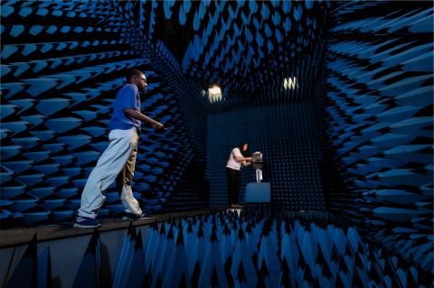 Two young men stand in a room covered in spikes of blue foam on all four walls, the floor and ceiling.