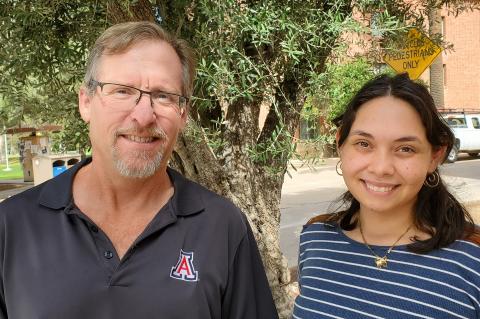 Greg Ogden and Carla Colon Cruz smile for a photo. They are outside in front of a tree.