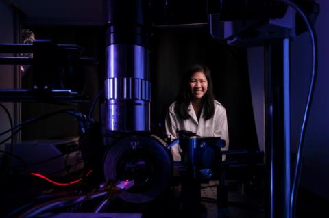 Judith Su in her lab with FLOWER. The lab is dark and lit with blue and purple lighting.
