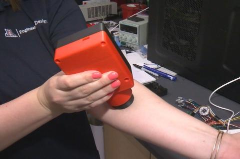Close up of a woman holding a plastic device onto her left arm.
