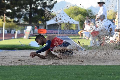Mo Almarhoun sliding in the dirt after completing a long jump.