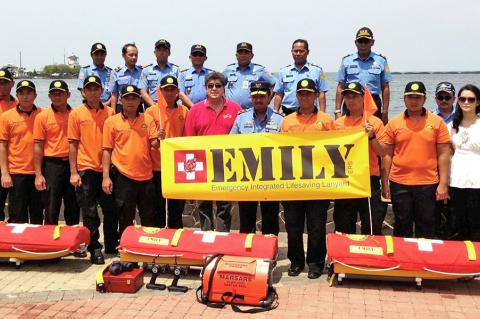 a large group of people pose near water with rescue equipment