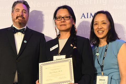 Three people pose with an award certificate