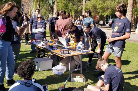 Students group around a table holding solar trackers