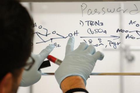 A man writing in marker on a window.