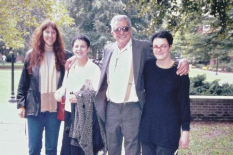 Four people (three women and one man) standing and smiling on a college campus.