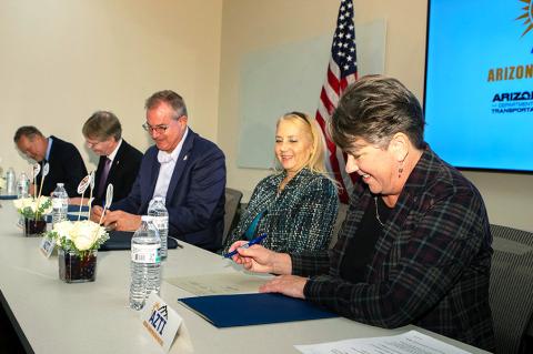 5 people sign documents at a table