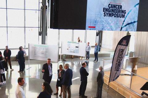 A small crowd of people in a large room with scientific poster displays