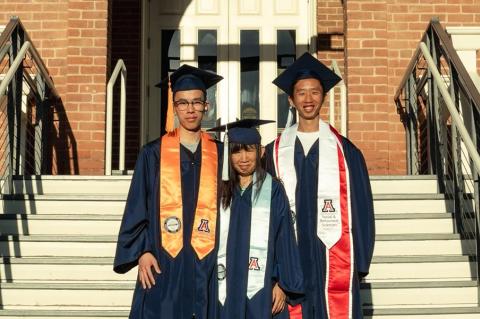 Three people pose on the steps of Old Main at the University of Arizona