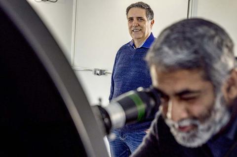 a scientist uses an optical instrument while another stands by