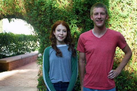 Two people standing in front of an ivy-covered archway on the UA campus.