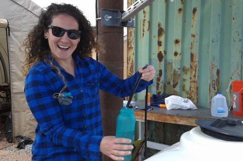 Vicky Karanikola smiling, wearing sunglasses and holding a water bottle.