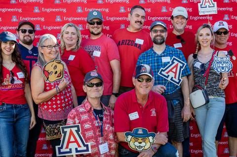 a group of people poses in front of a backdrop at the Homecoming tailgate