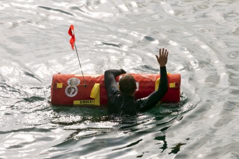 A swimmer in a wet suit holds onto an EMILY robotic rescue buoy