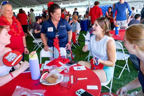 a group of students and faculty at an event table