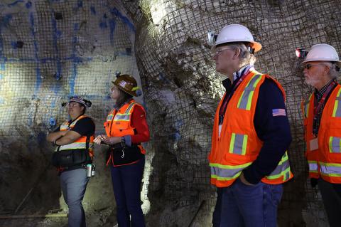 5 people wearing hard hats stand inside a mind