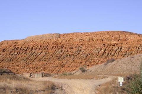 A pile of mine tailings against a blue sky.