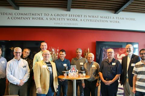 A group of 11 stands around a table holding award medallions