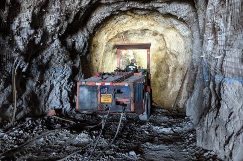 A piece of mining equipment preparing to bore into a gray rock wall