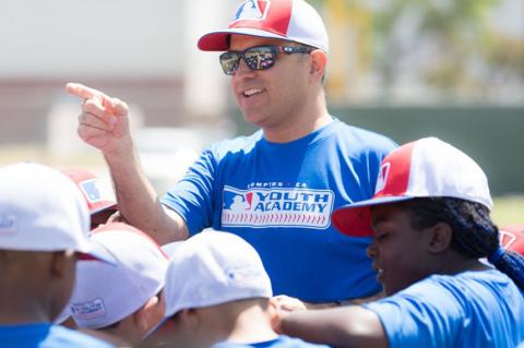 Ricardo Valerdi addresses a group of children in baseball caps outdoors