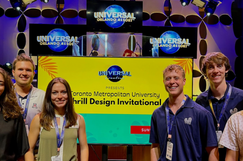 six students stand in front of a conference display