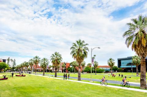 A shot of the UA Mall on a sunny day. Students are riding bikes and walking in the sunshine.