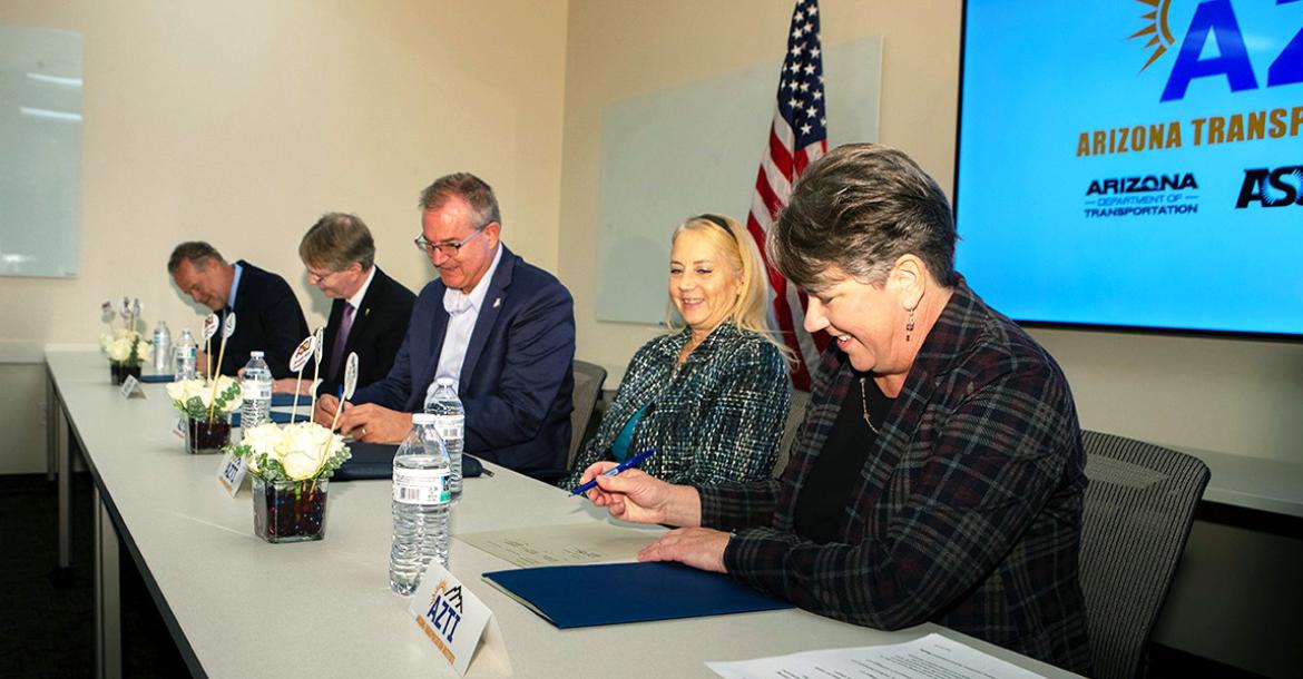 5 people sign documents at a table