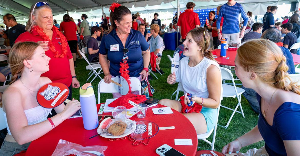 a group of students and faculty at an event table