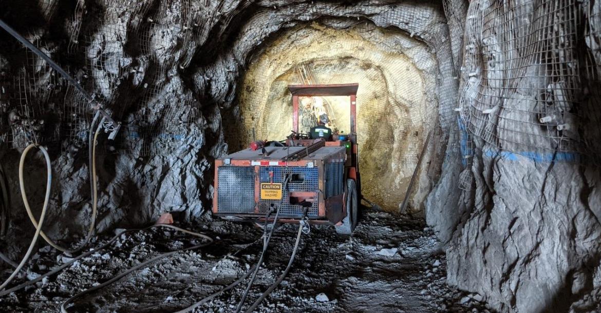 A piece of mining equipment preparing to bore into a gray rock wall