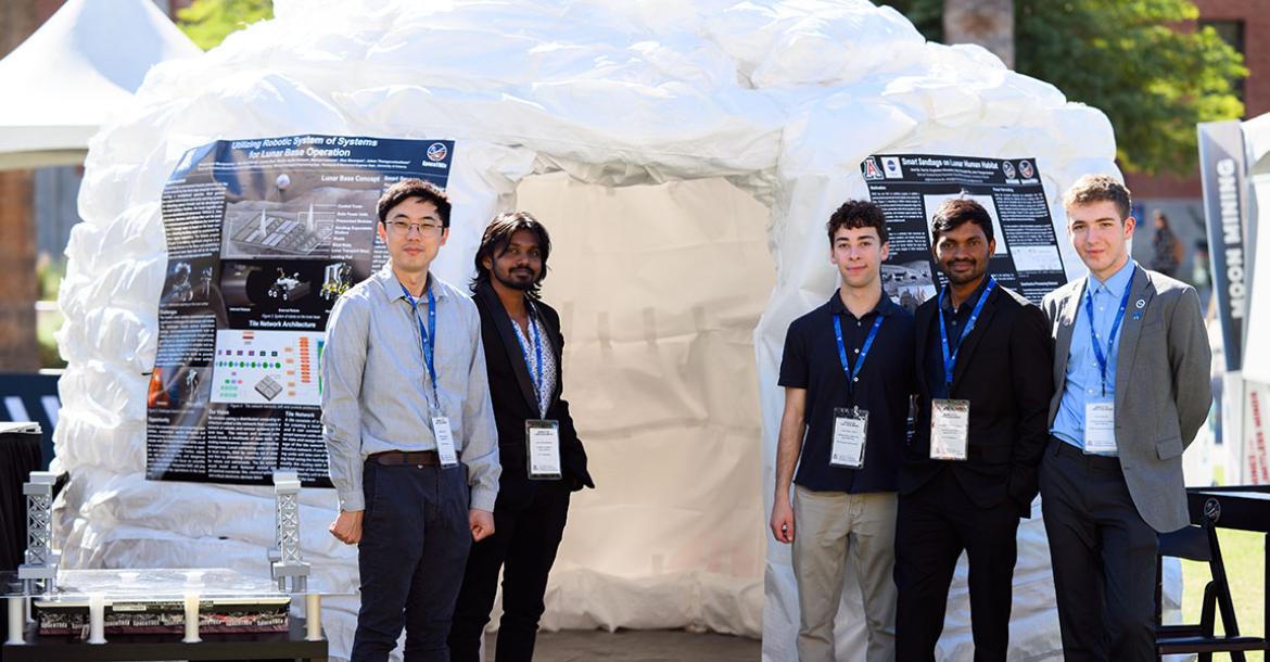 Students stand in front of the tall sandbag structure outdoors