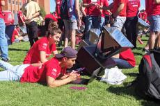 A student checks the rising temperature of his team's solar oven.