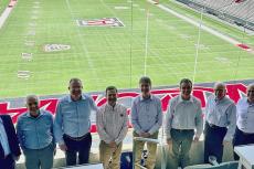 Eight engineering deans from Pac-12 universities stand in the UA football stadium with the football field behind them