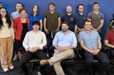 A group of instructors poses indoors, with one row sitting and one standing