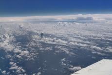A photo of the top of the cloud layer, taken from a plane. The wing of the plane is visible in the bottom right of the photo.