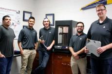 Five students standing by a 3D printer