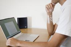 a person models the device while sitting at desk with a computer