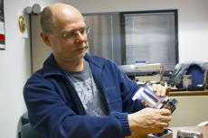 Wolfgang Fink holding up a metal, binocular-like device.