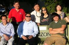 A family group of 7 gathers around a memorial bench on the University of Arizona campus