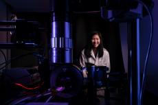 Judith Su in her lab with FLOWER. The lab is dark and lit with blue and purple lighting.