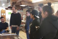 A group of students gather around to watch a demonstration.