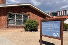 A red brick building is pictured with a blue sign in the front.