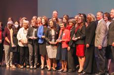 Women of Impact awardees stand on a stage