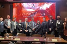 a large group of panelists poses in a conference setting