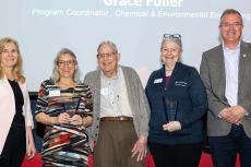 Five people pose with two award statues