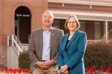 Two people sit in front of the Old Main building on the UA campus