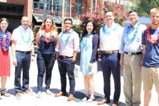 Eight faculty members smiling and wearing red and blue leis.