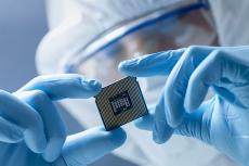 A gloved worker holds a computer chip